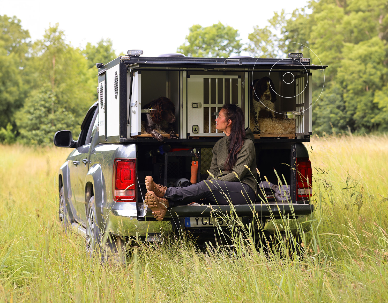 A woman with two dogs in a car crate equipped with MiniFinder Zenso, monitoring temperature and humidity for a safe transport environment.