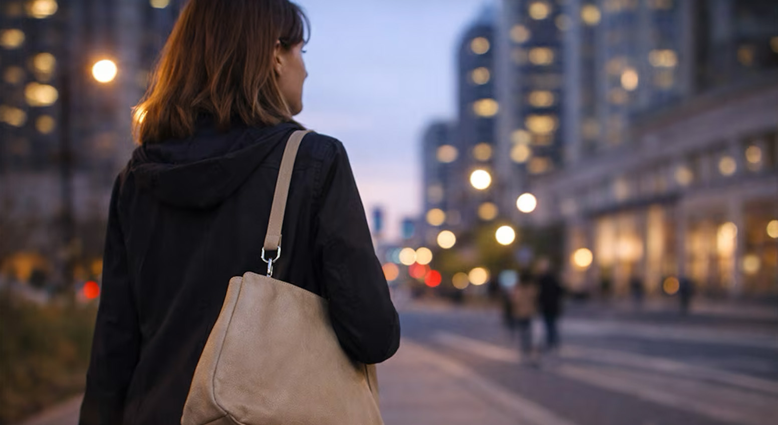 Woman walking alone in the city at dusk with a personal alarm attached to her bag